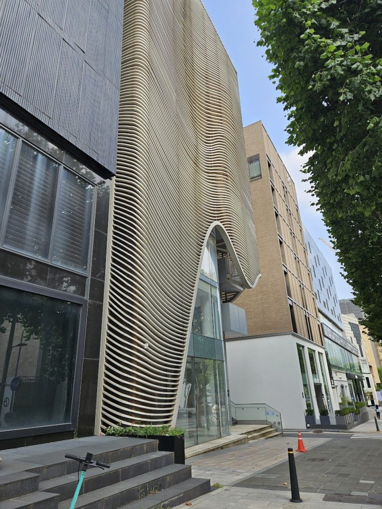 Curved timber screen wrapping a facade with soft vertical rhythm in Seoul.