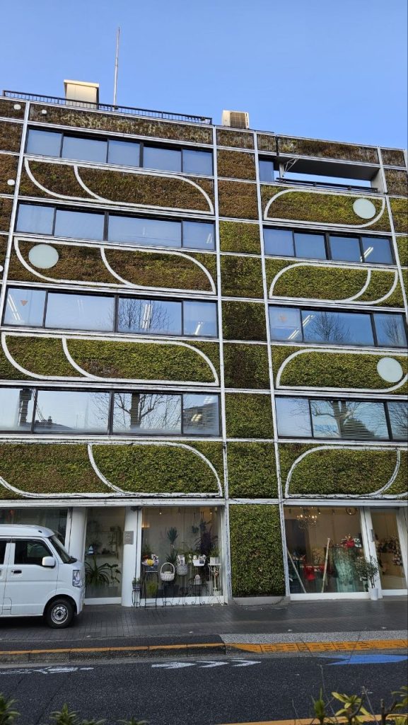 Planted street facade where a rigid grid is softened by greenery and colour.