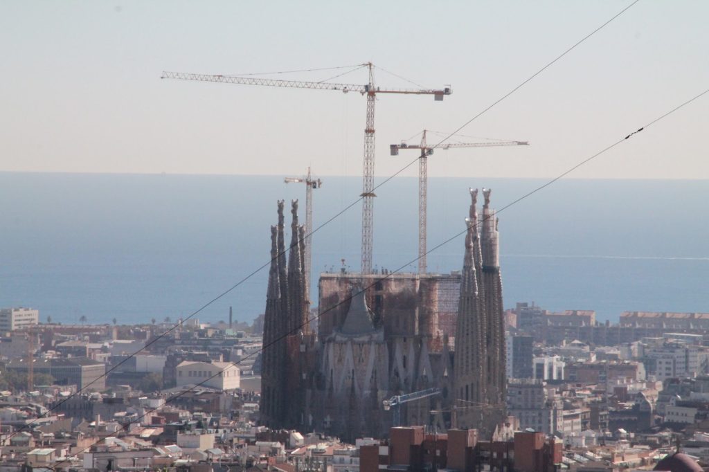 Distant Barcelona city view with construction cranes, skyline, and landmark form.