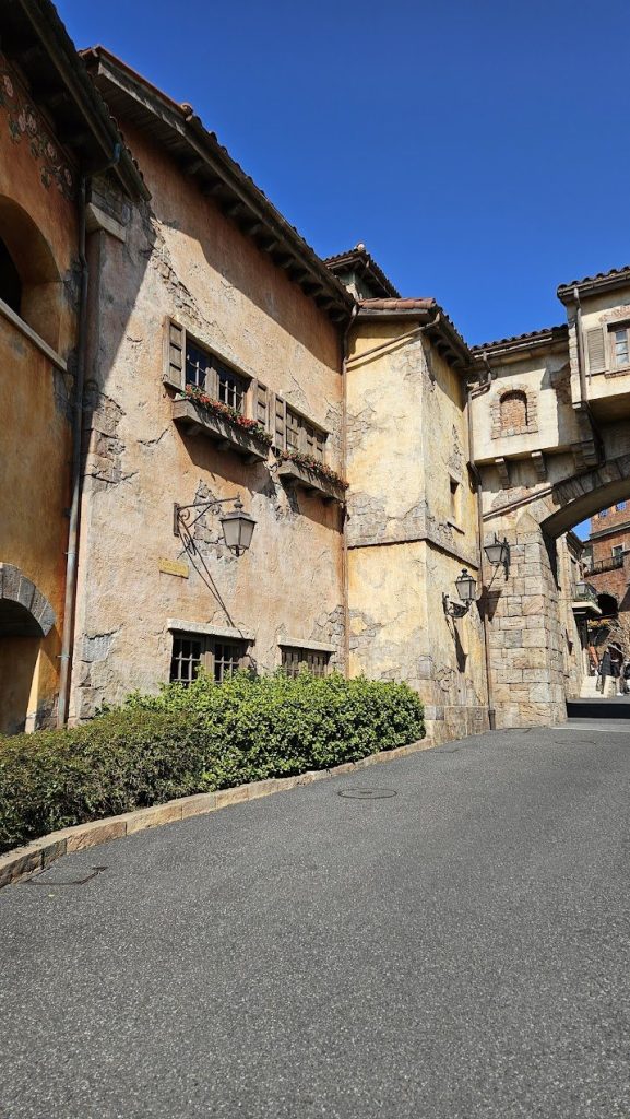 Warm village lane with stucco, stone, windows, and textured architectural edges.