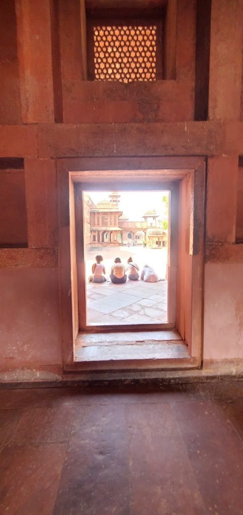 Red sandstone doorway framing a quiet threshold between shadow and courtyard light.
