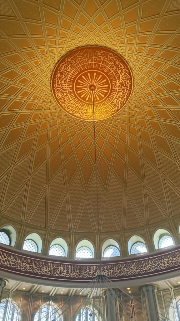 Patterned dome ceiling gathering daylight, ornament, and geometric structure overhead.