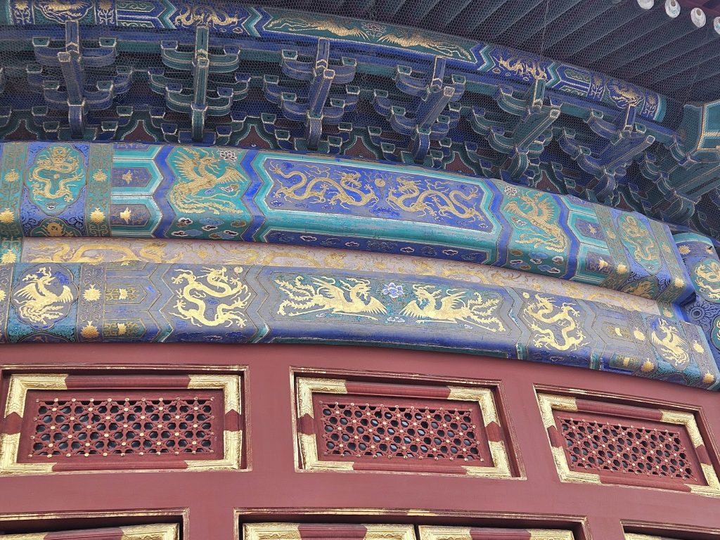 Painted timber beams layered with blue, gold, and red ornamental pattern.
