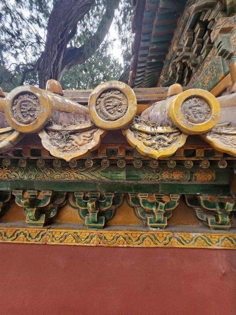 Close view of glazed roof tiles with yellow colour, ornament, weathering, and repetition.
