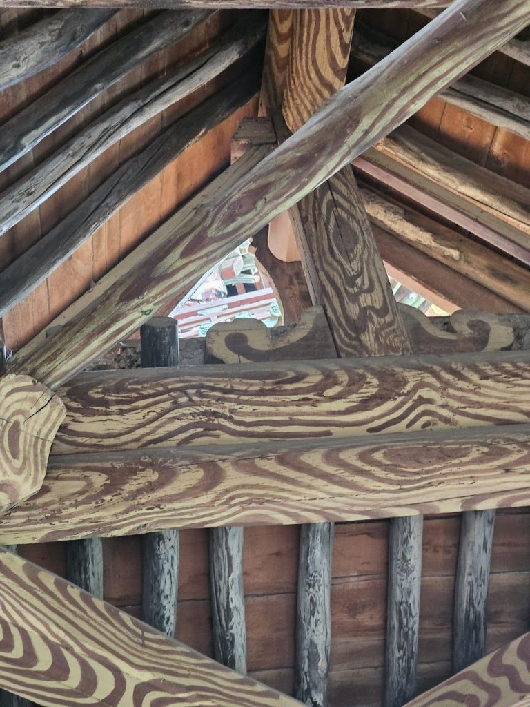 Layered timber roof members showing joinery, grain, structure, and shadow.