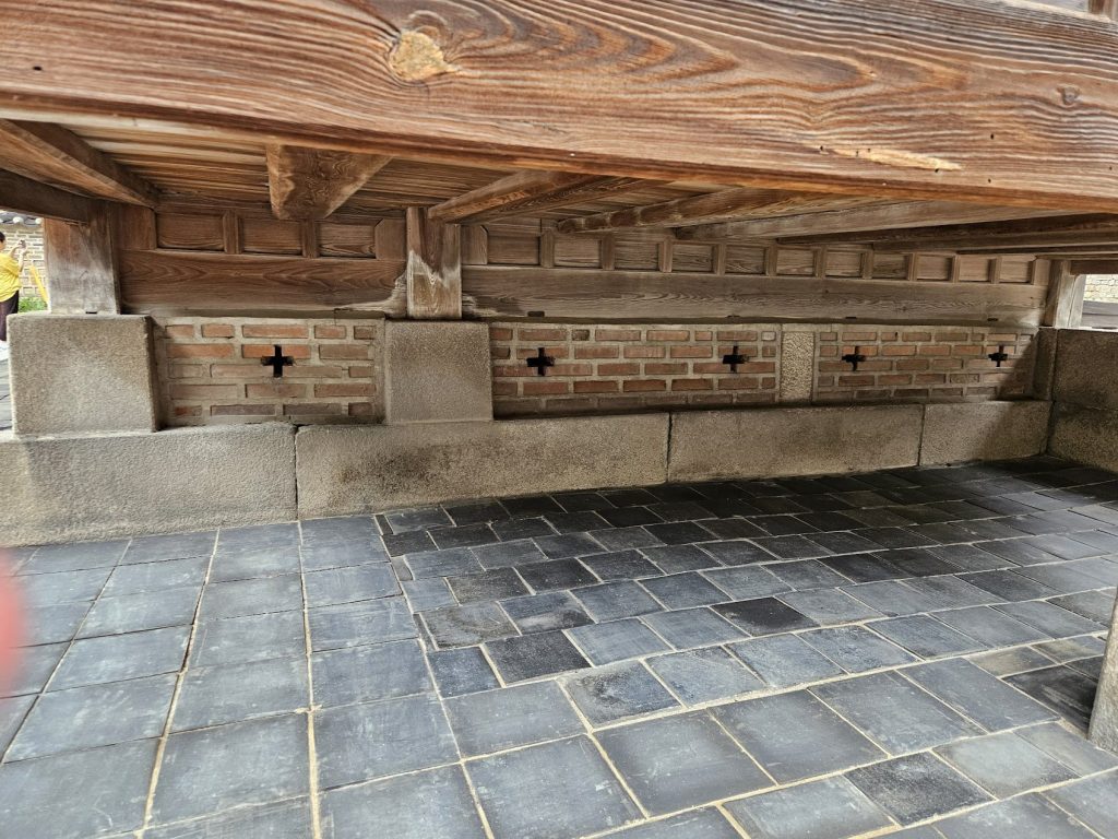 Timber, brick, stone, and floor tile meeting in a low architectural base condition.